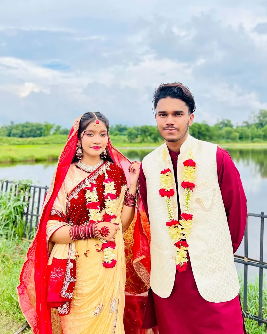 The couple standing by a lake under a cloudy sky