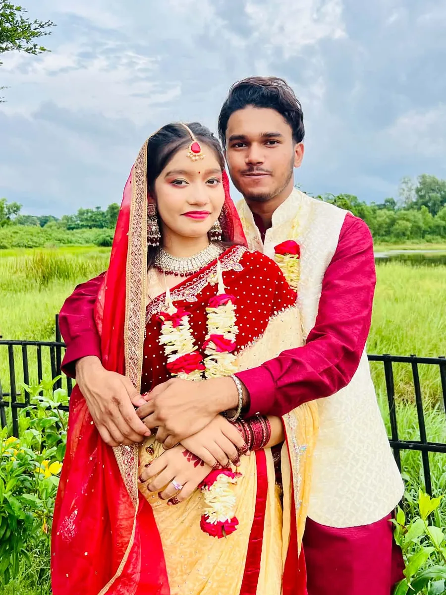 Efran holding Orna close beside a lake, both in wedding clothes